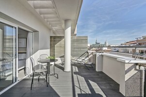 Un balcone con tavolo e sedie, vista sulla città e un edificio con una cupola.