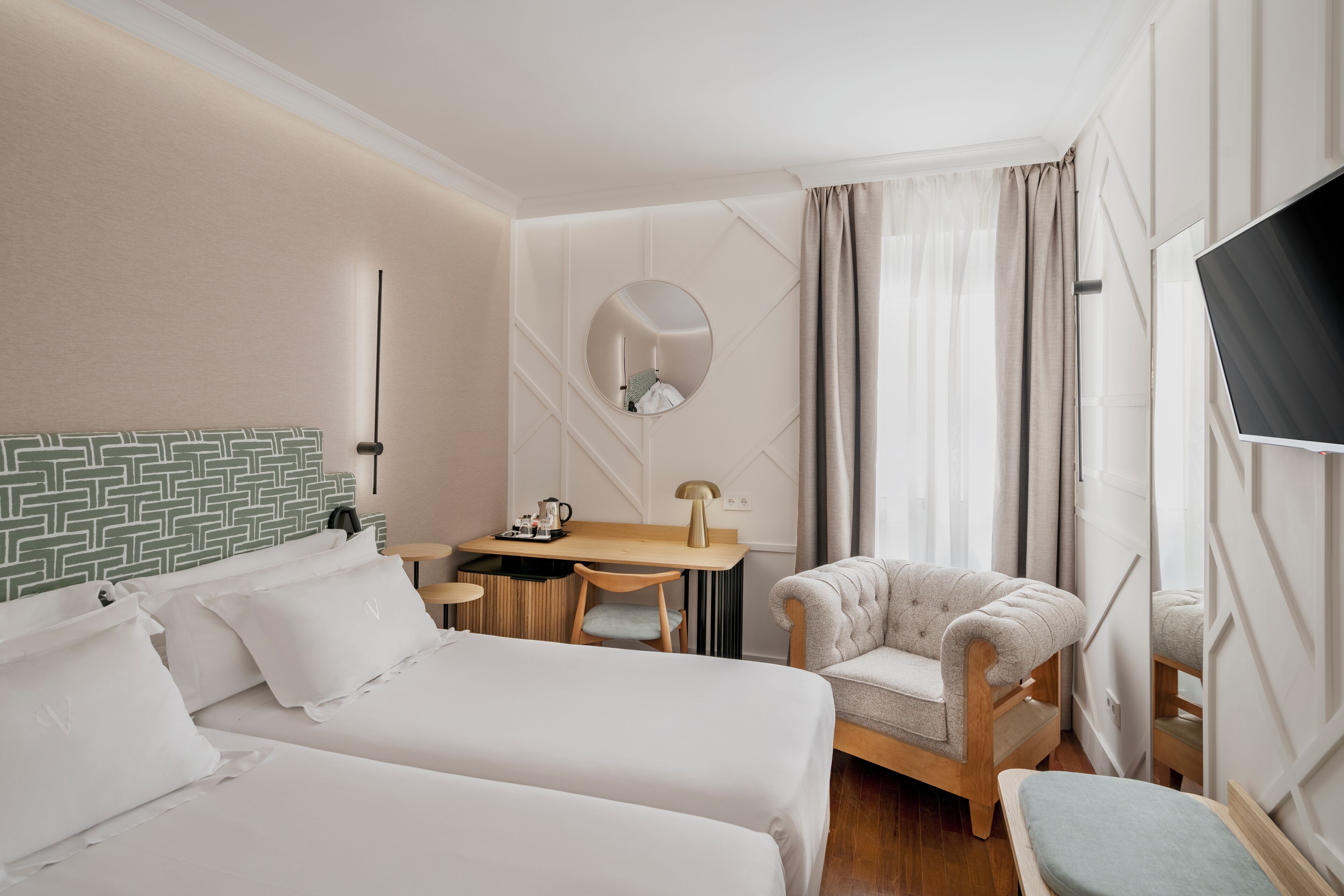 Une chambre d’hôtel avec deux lits, un bureau, une chaise, une télévision et un miroir.