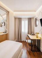 A hotel room with a bed, a desk, a chair, a television, and a window with curtains.