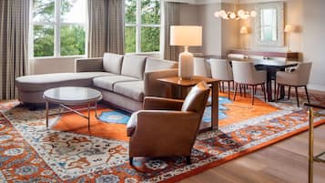 A modern living room with a sofa, armchairs, a coffee table, and a dining area with chairs and a table.