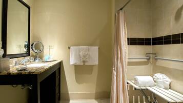 A bathroom with a sink, mirror, towel rack, and shower area.