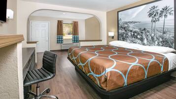 A hotel room with a bed, a desk, and a large window with a beach view.