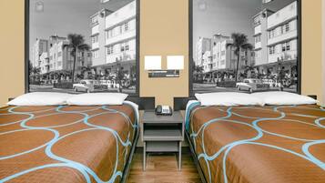 Une chambre d’hôtel avec deux lits, une table de chevet avec un téléphone et une vue sur une rue bordée de palmiers et de voitures.