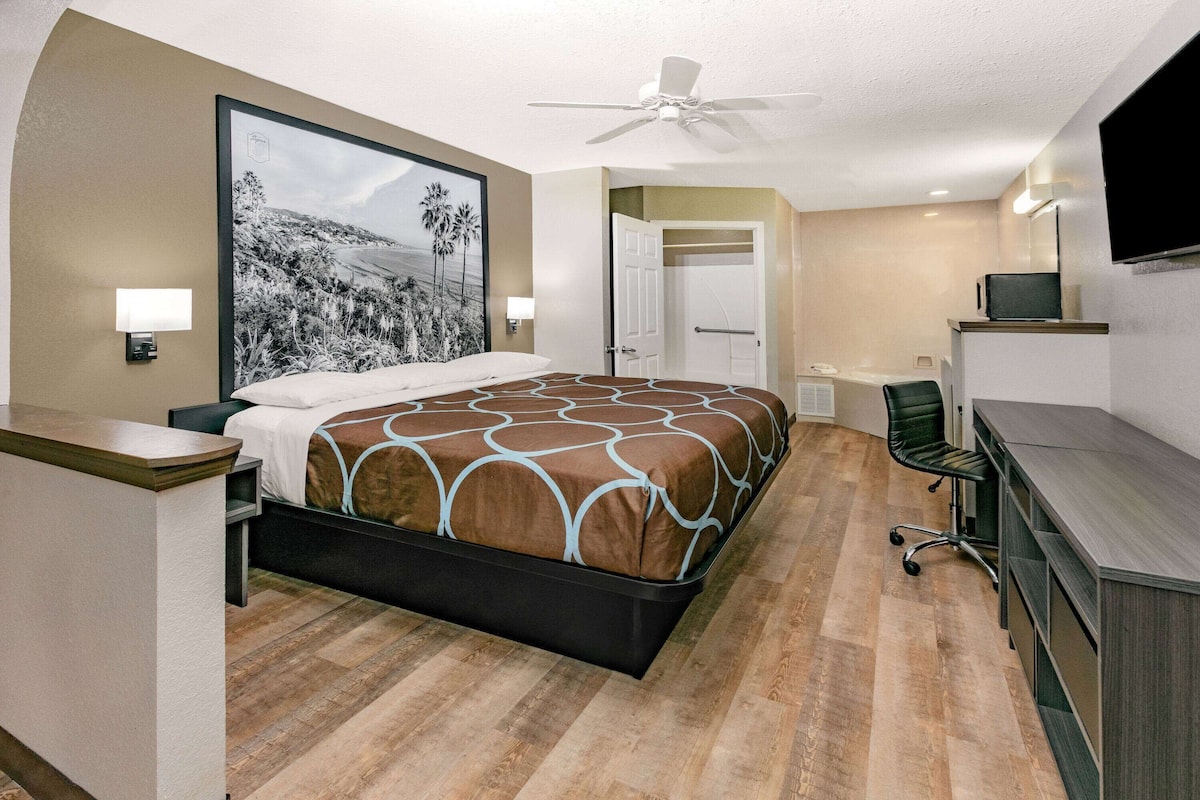 A hotel room with a bed, desk, chair, and a TV.