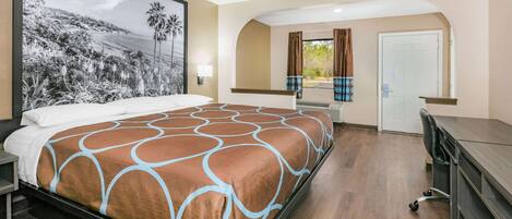 Una habitación de hotel con una cama grande, un escritorio y vistas a un cuadro de paisaje.