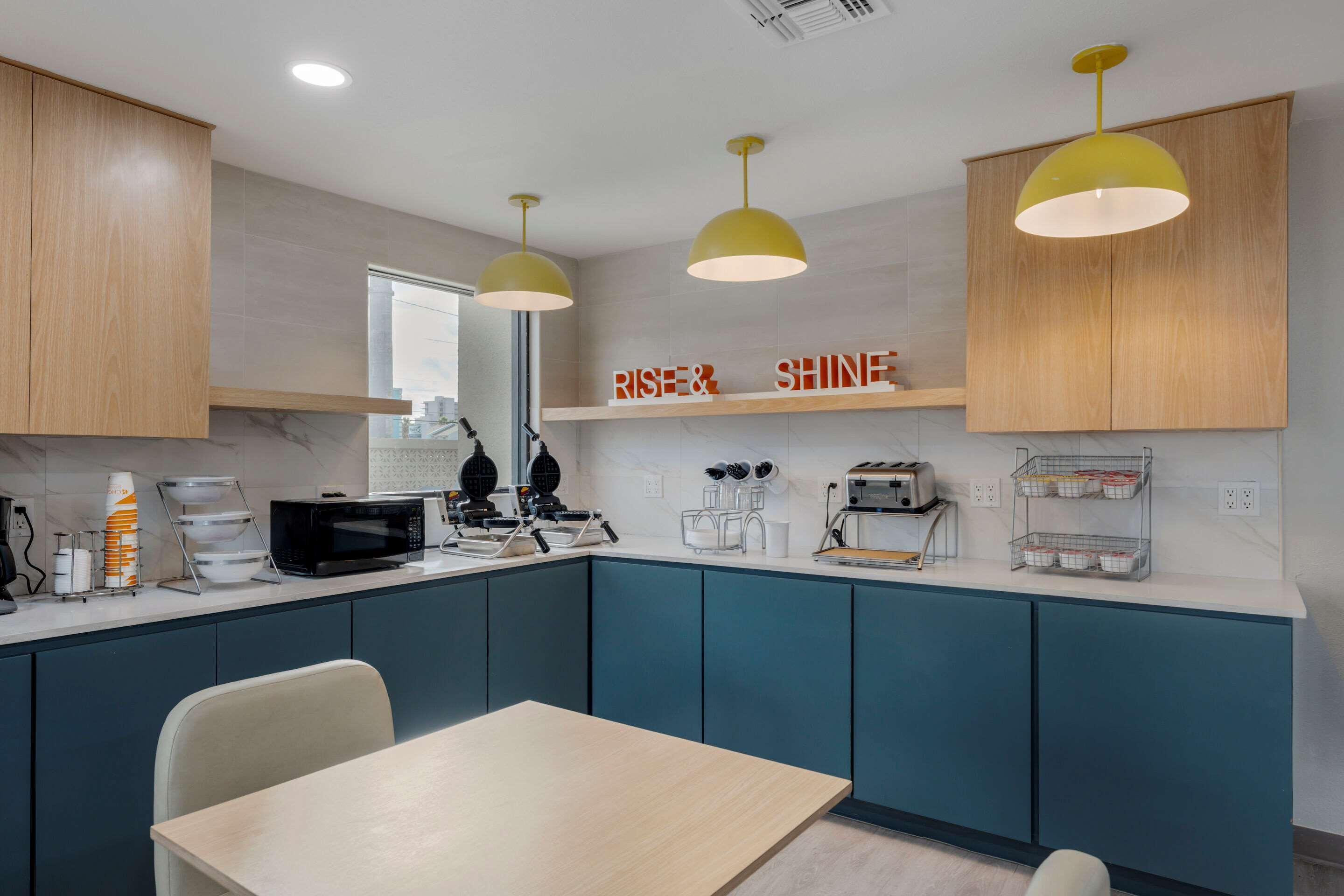 Une cuisine moderne avec des armoires de couleur turquoise, un plan de travail en bois et un coin repas comprenant une table et des chaises.