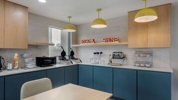 A modern kitchen with teal cabinets, a wooden countertop, and a dining area with a table and chairs.