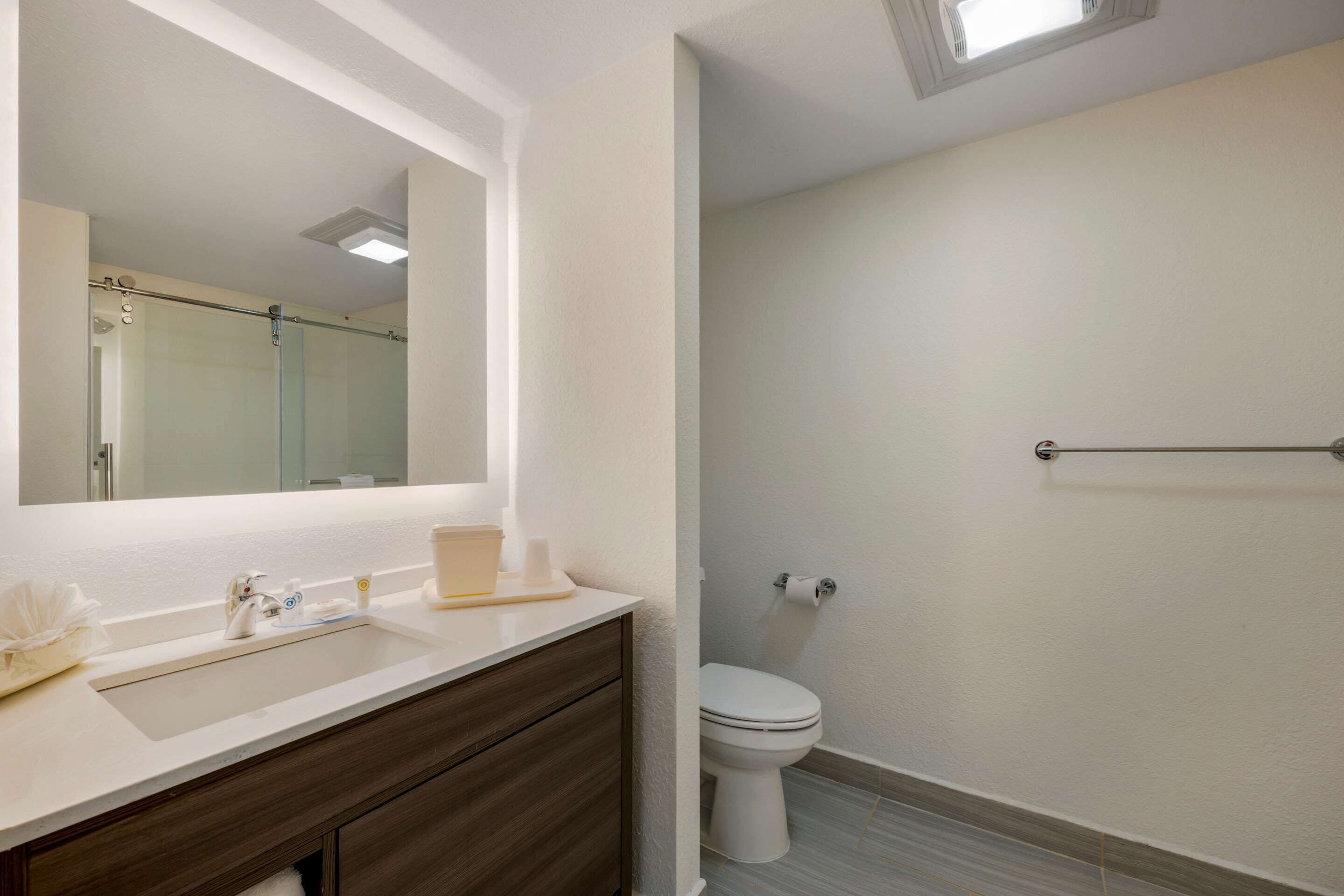 A modern bathroom with a white sink, dark wooden vanity, and a glass shower enclosure.