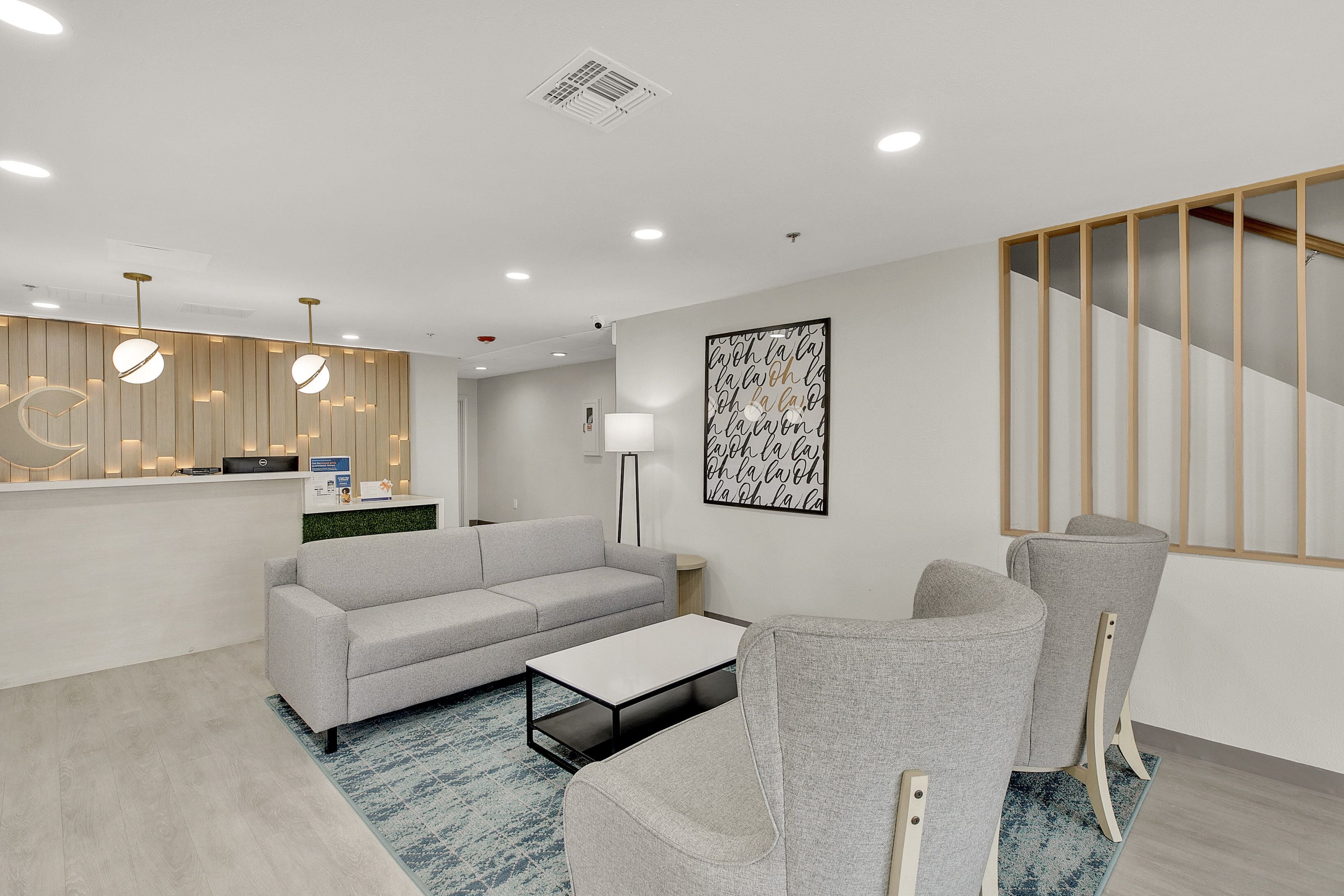Eine moderne Hotellobby mit grauem Sofa, einem Couchtisch und einer Rezeption.