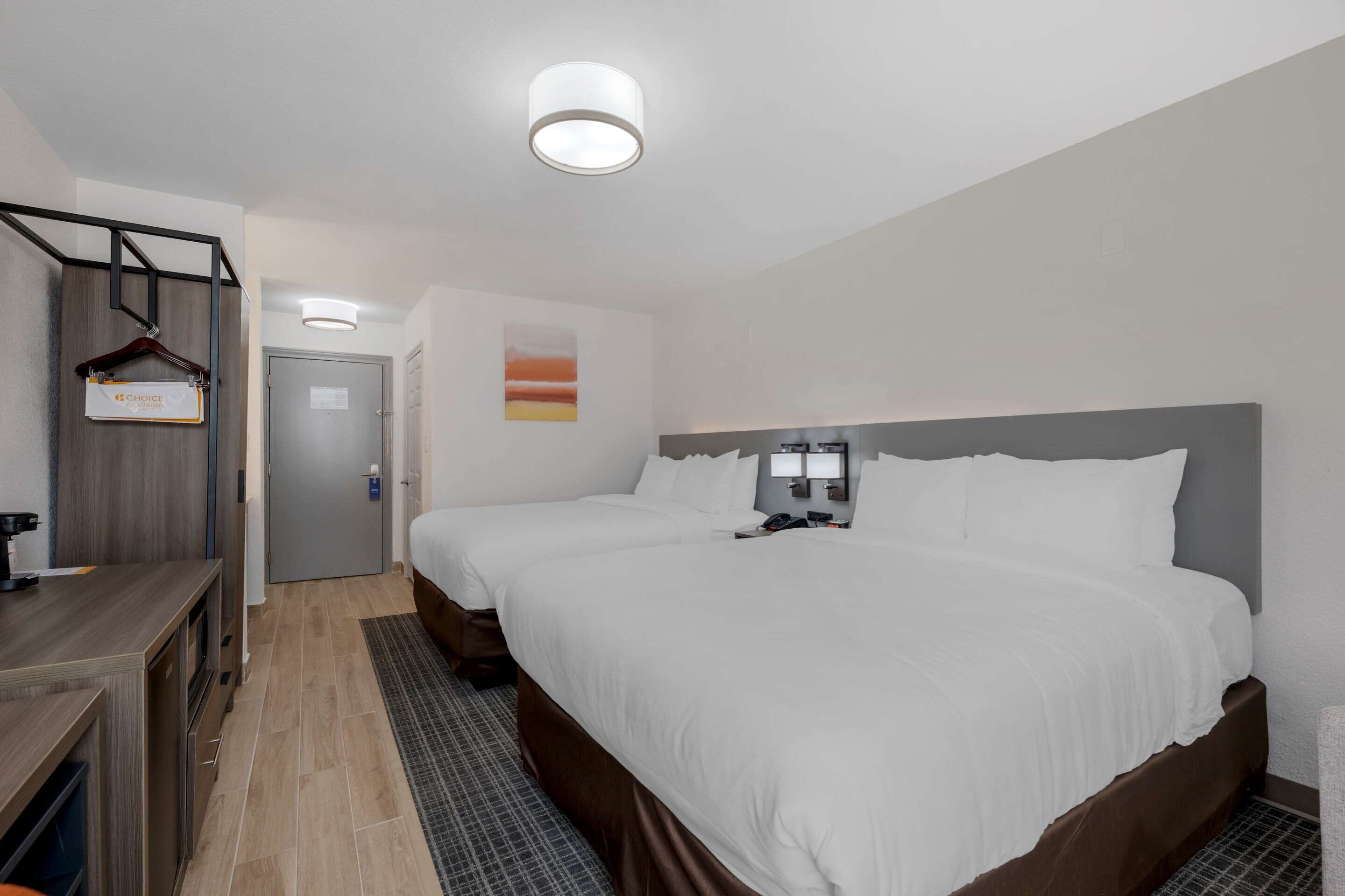 Habitación de hotel con una cama grande, un escritorio con silla, un armario y una puerta.
