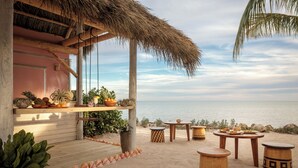 A beachside patio with wooden furniture, a thatched roof, and a view of the ocean. - Islander Resort (Islamorada)