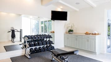A home gym with exercise equipment, a television, and a kitchen area.