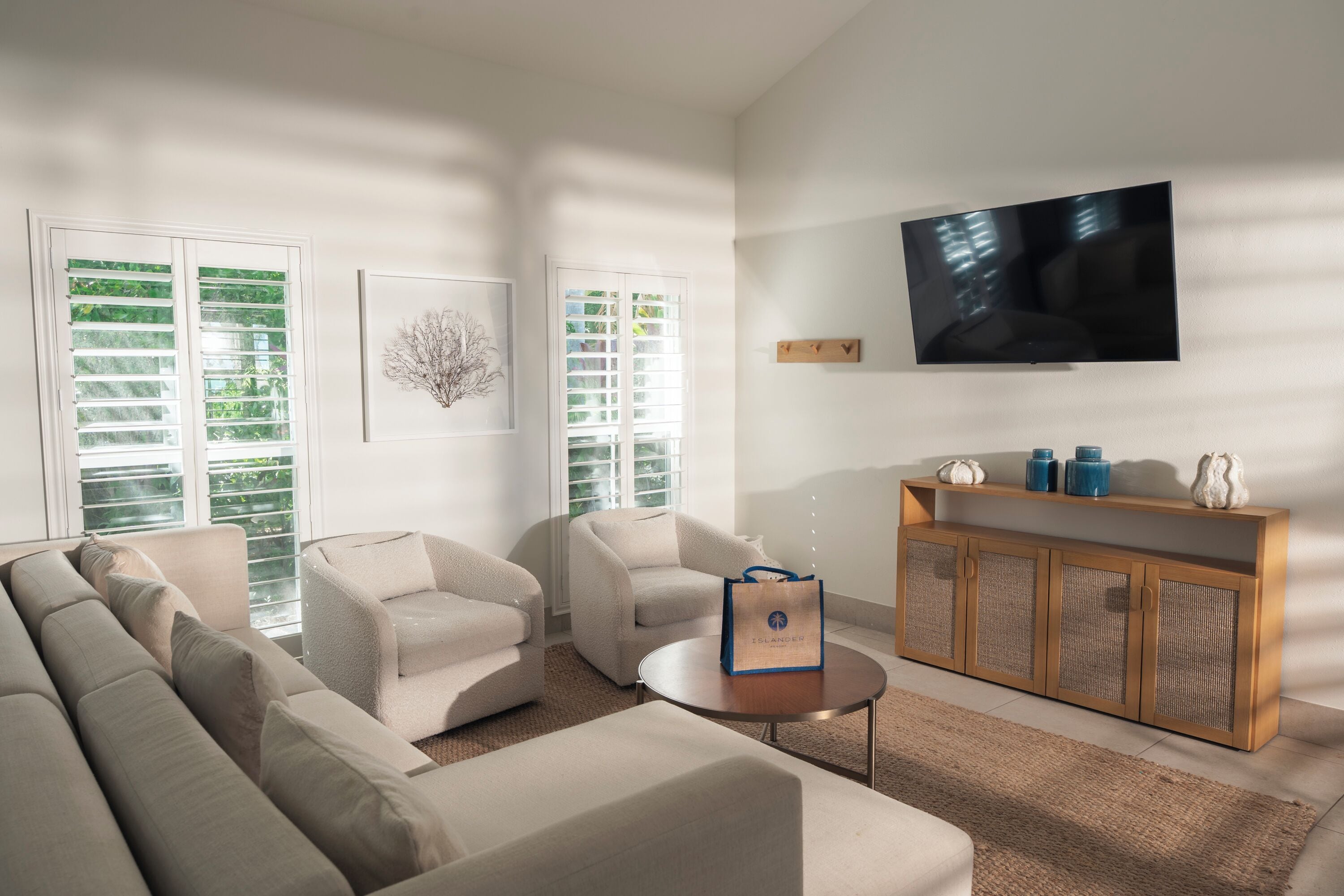 A modern living room with a sofa, armchairs, a coffee table, and a TV mounted on the wall.
