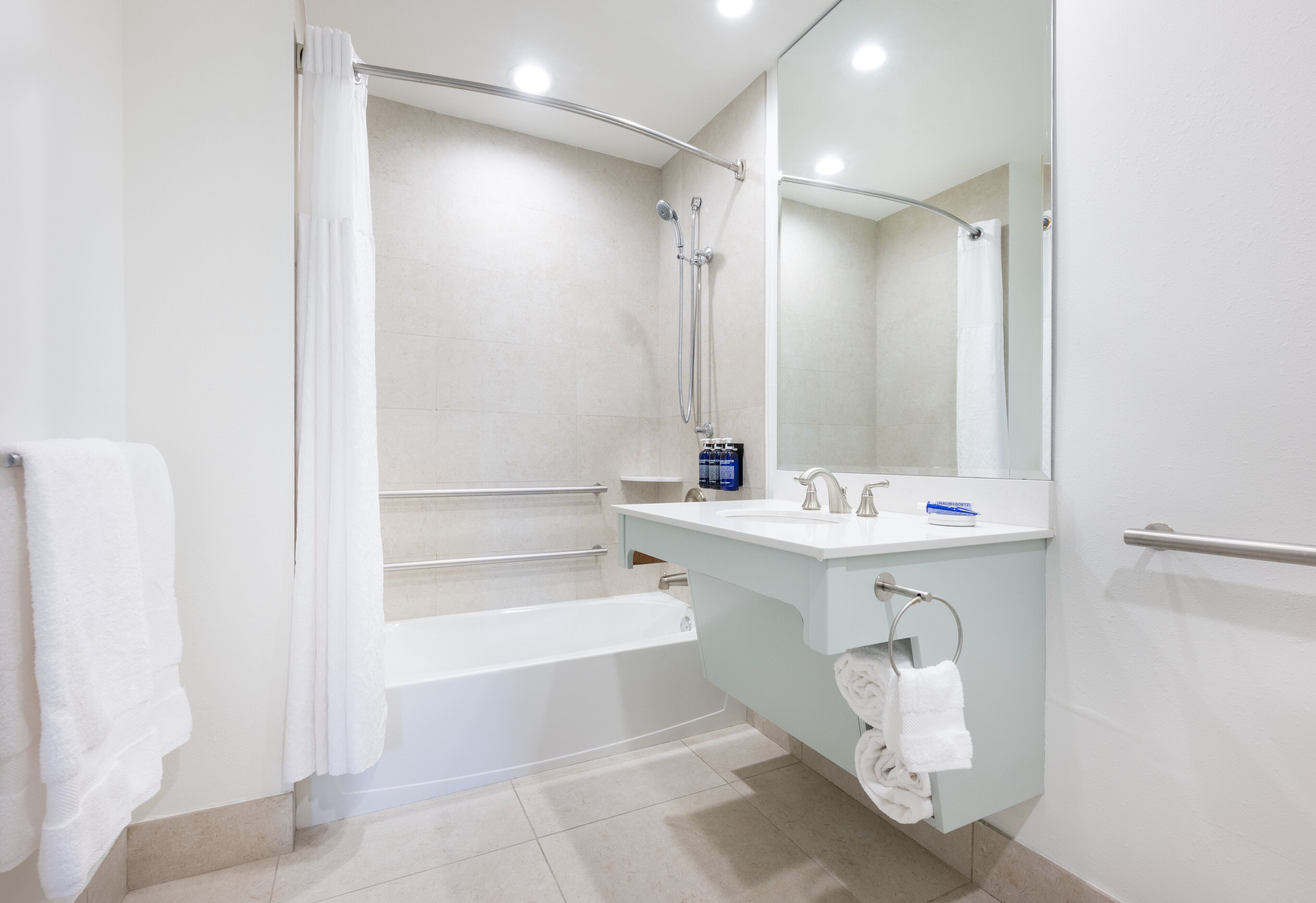 A modern bathroom with a bathtub, shower, and vanity with a mirror.