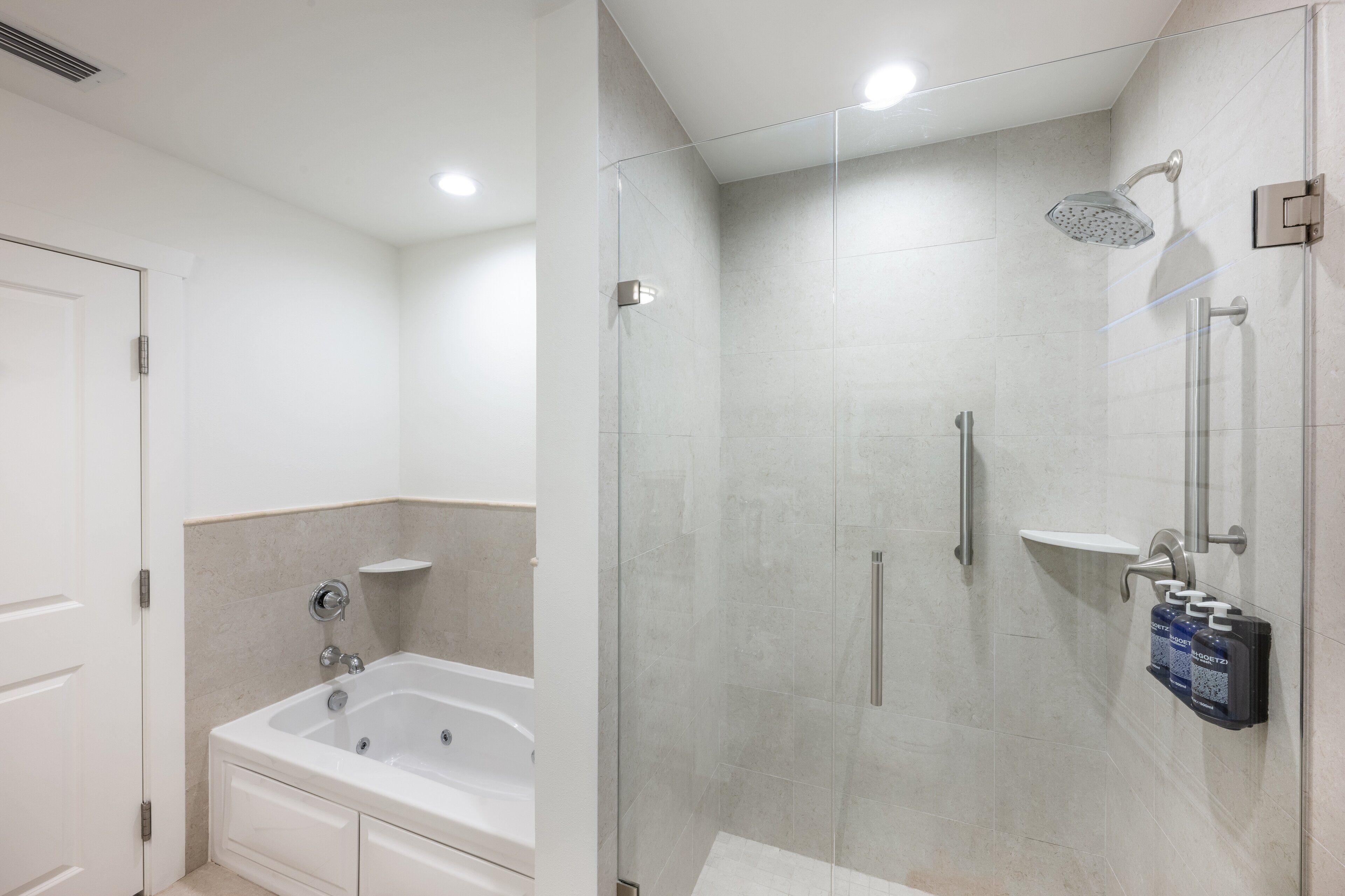 A modern bathroom with a glass-enclosed shower, a standalone bathtub, and a towel rack with toiletries.