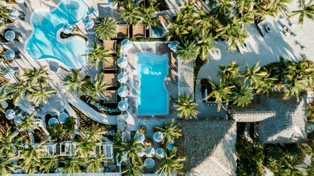 An aerial view of a resort with two swimming pools surrounded by palm trees and sun loungers. - Islander Resort (Islamorada)