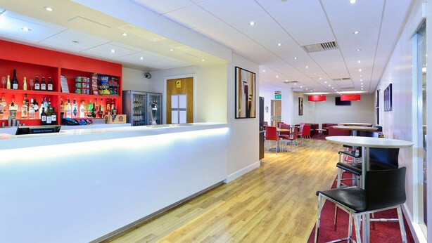 A modern bar area with a counter, shelves of beverages, and seating for guests. - Travelodge Aberdeen Central (Aberdeen)