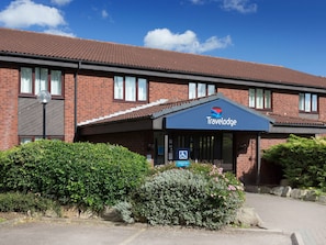 A Travelodge hotel with a brick facade, large windows, and a covered entrance. - Travelodge Nuneaton Bedworth (Nuneaton)