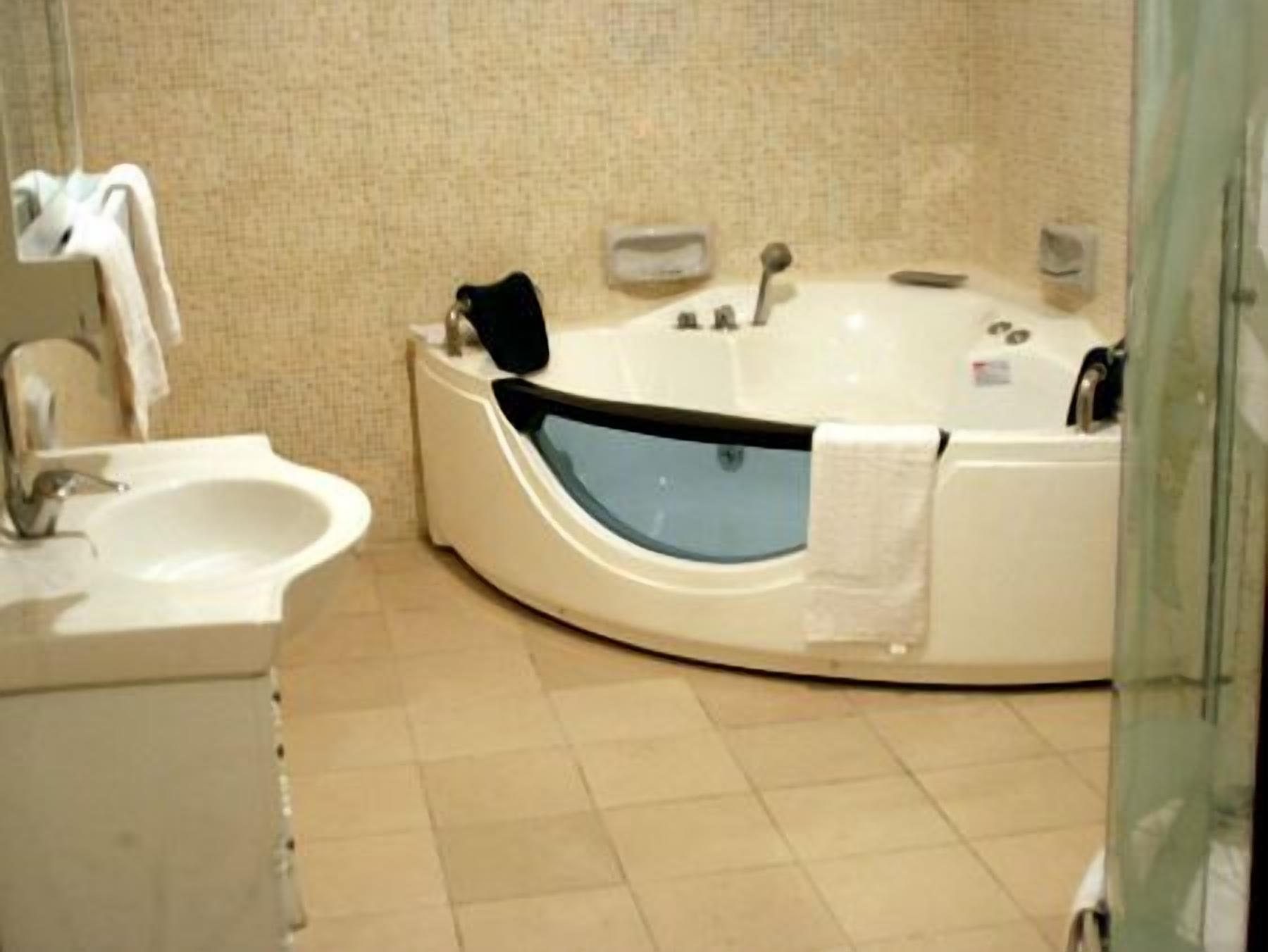 A bathroom with a bathtub, a sink, and a mirror.