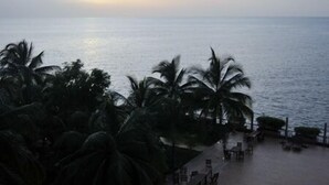 A beachfront view with palm trees and a seating area. - Mariador Palace (Conakry)