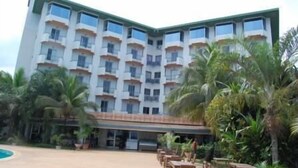 A multi-story hotel with a symmetrical facade, balconies, and a pool area with outdoor seating. - Mariador Palace (Conakry)