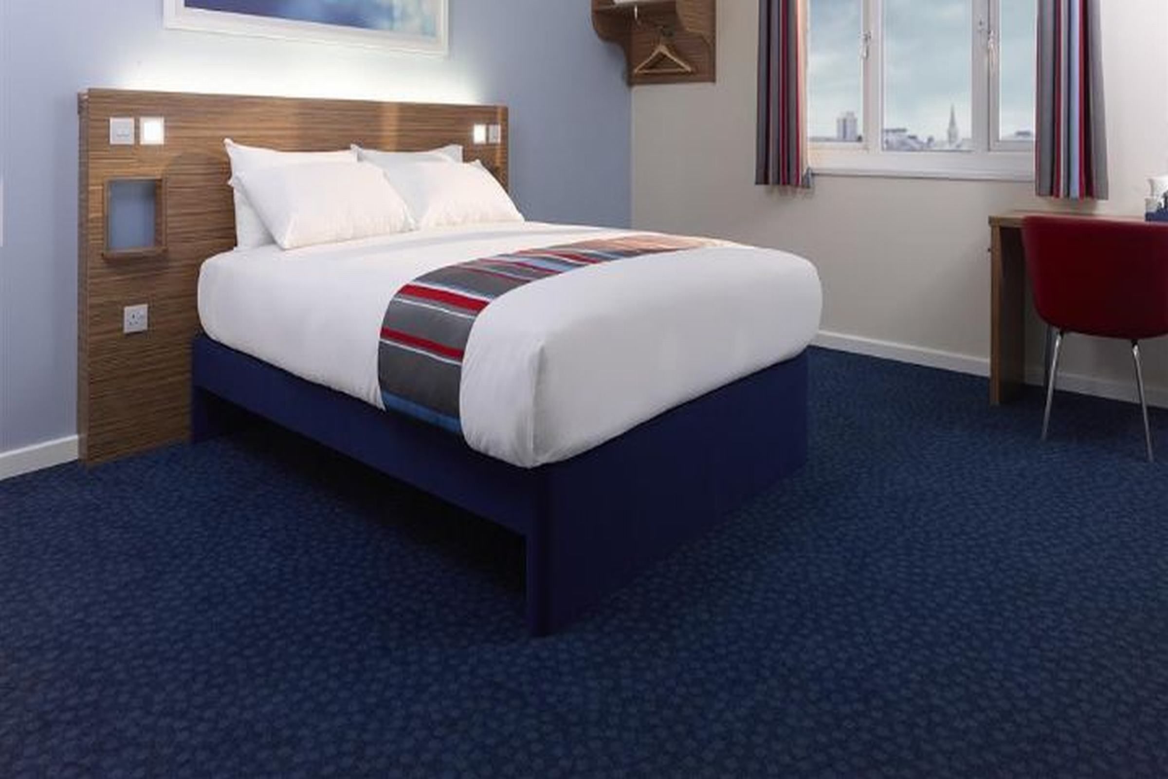 A hotel room with a bed, a desk, and a chair.