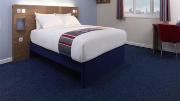 A hotel room with a bed, a desk, and a chair.