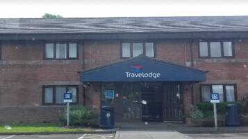 A Travelodge hotel with a brick facade, a covered entrance, and a parking area with disabled parking signs.