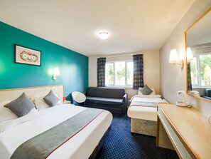 A hotel room with a bed, a sofa, a desk, and a window with curtains. - OYO Sunrise Hotel, A46 N Leicester (Leicester)