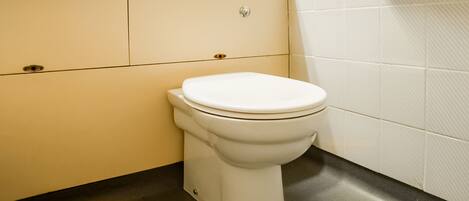 A bathroom with a toilet, sink, and toilet paper holder.