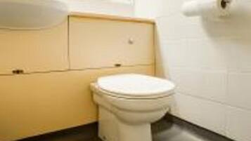 Un baño pequeño y funcional con inodoro, lavamanos y espejo.