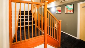A wooden staircase with a handrail, carpeted steps, and a wall with framed pictures. - OYO Sunrise Hotel, A46 N Leicester (Leicester)