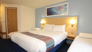 A hotel room with a large bed, two bedside tables, a wooden headboard, and a framed picture on the wall. - Travelodge Grantham South Witham (Grantham)