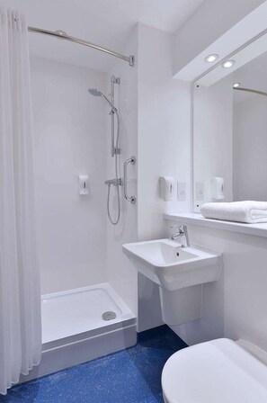 A modern bathroom with a walk-in shower, a pedestal sink, a toilet, and a mirror. - Travelodge Stirling M80 (Stirling)