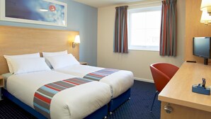 A hotel room with a double bed, a desk with a computer, a chair, a TV, and a window with curtains. - Travelodge Glasgow Central (Glasgow)