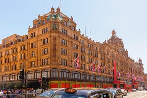 A large, ornate building with multiple flags, a dome, and a prominent clock tower. - Travelodge Park Royal (London)