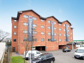 A Travelodge hotel with multiple floors, a brick facade, and several parking spaces. - Travelodge Park Royal (London)