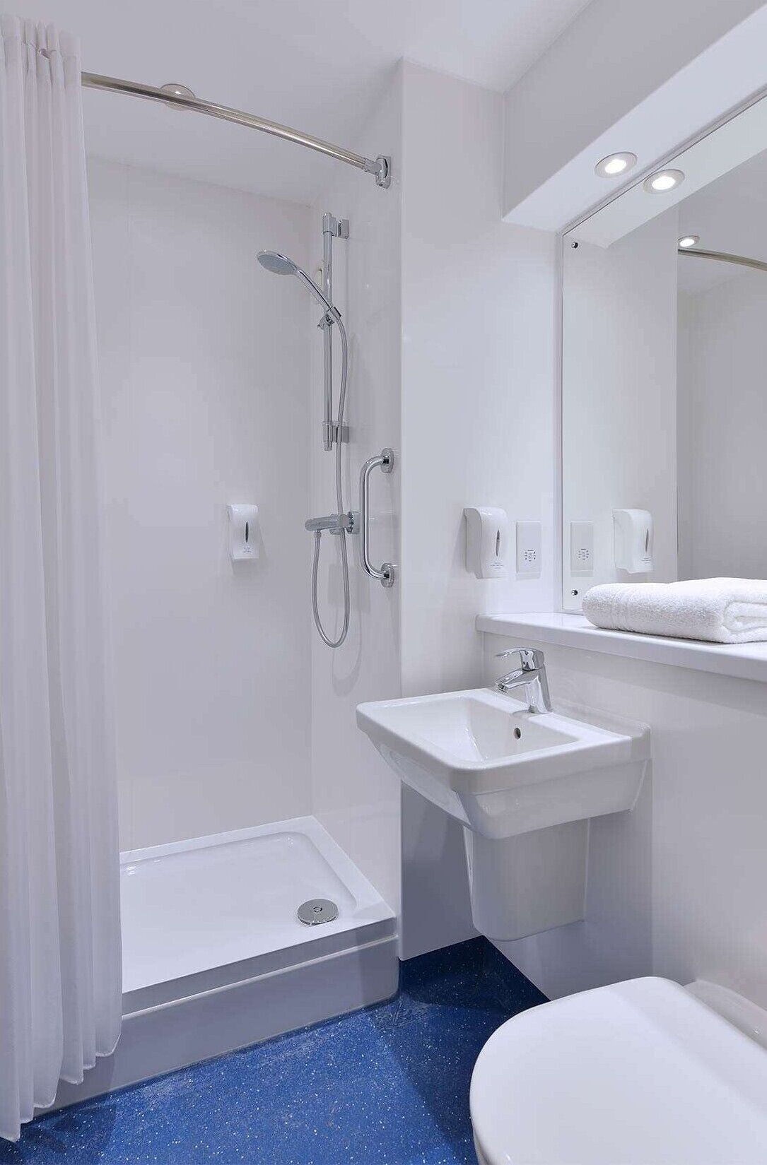 A modern bathroom with a walk-in shower, a pedestal sink, a toilet, and a mirror.