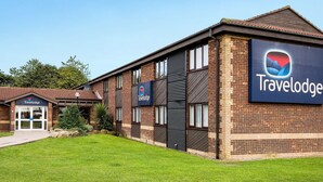 Ein Travelodge Hotel mit Backsteinfassade, großen Fenstern und einem gepflegten Rasen.
