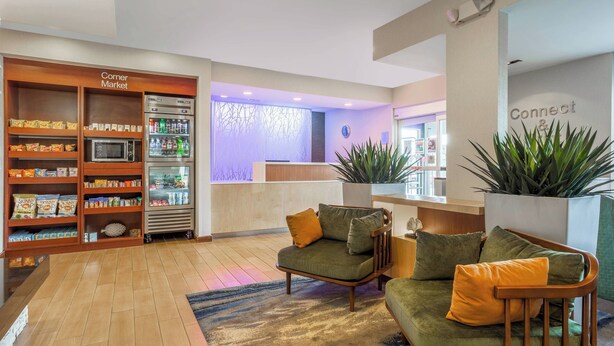 A lobby with a reception desk, a corner market with snacks and beverages, and seating areas with cushions. - Fairfield Inn By Marriott Indianapolis Northwest (Indianapolis)