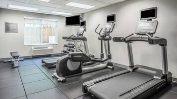Een fitnessruimte met loopbanden, elliptische trainers en een gewichtbank.