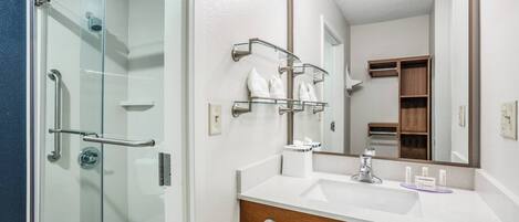 A modern bathroom with a glass shower enclosure, a vanity with a mirror, and a towel rack.