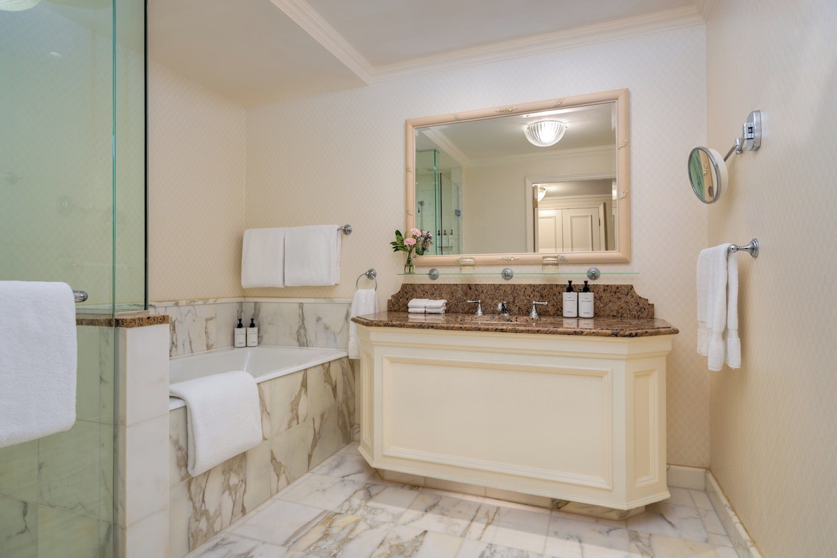 Un baño con tocador de mármol, un espejo grande y una cabina de ducha de vidrio.