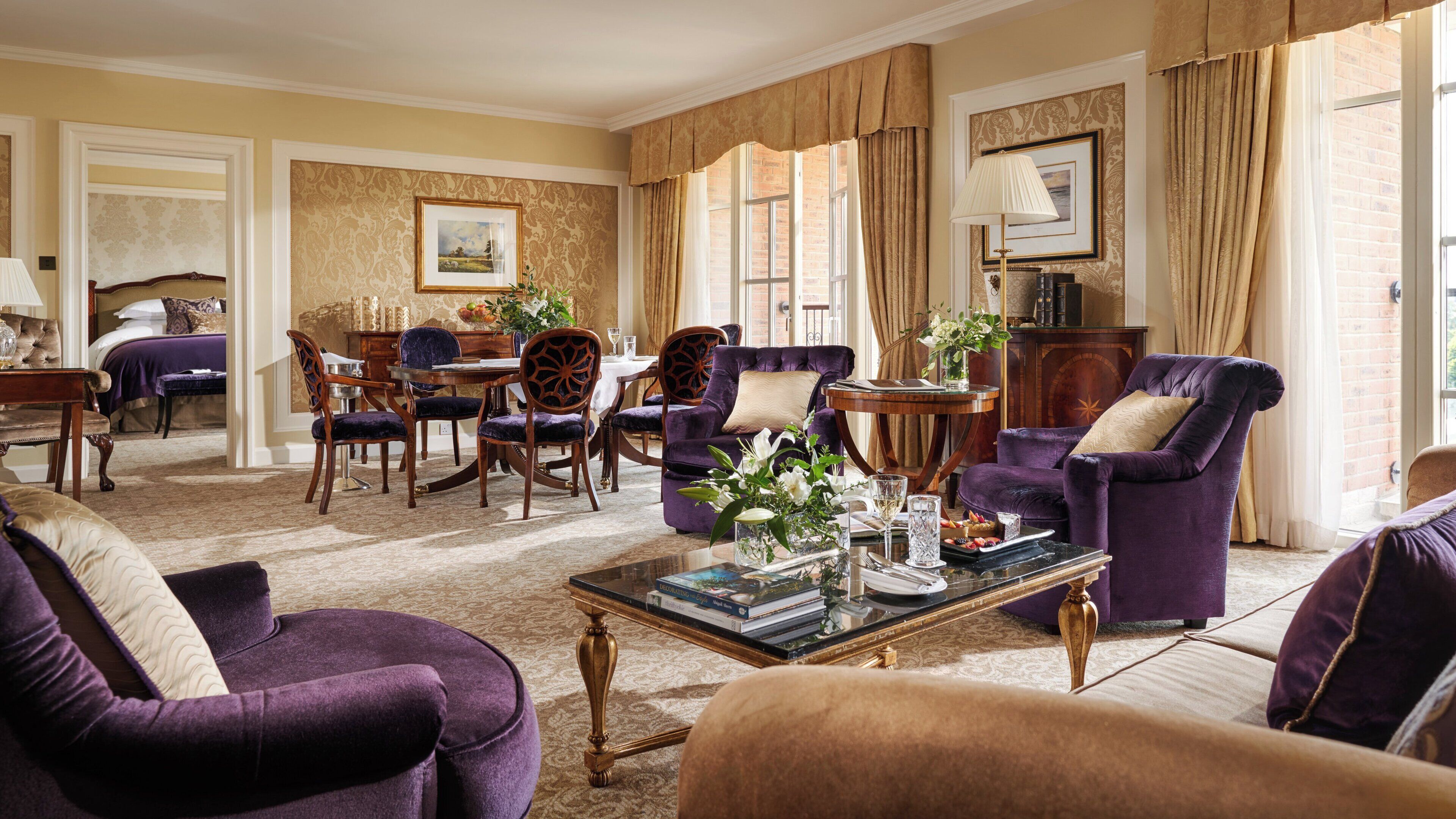 A well-appointed living room with a dining area, featuring classic furniture and a large window with curtains.