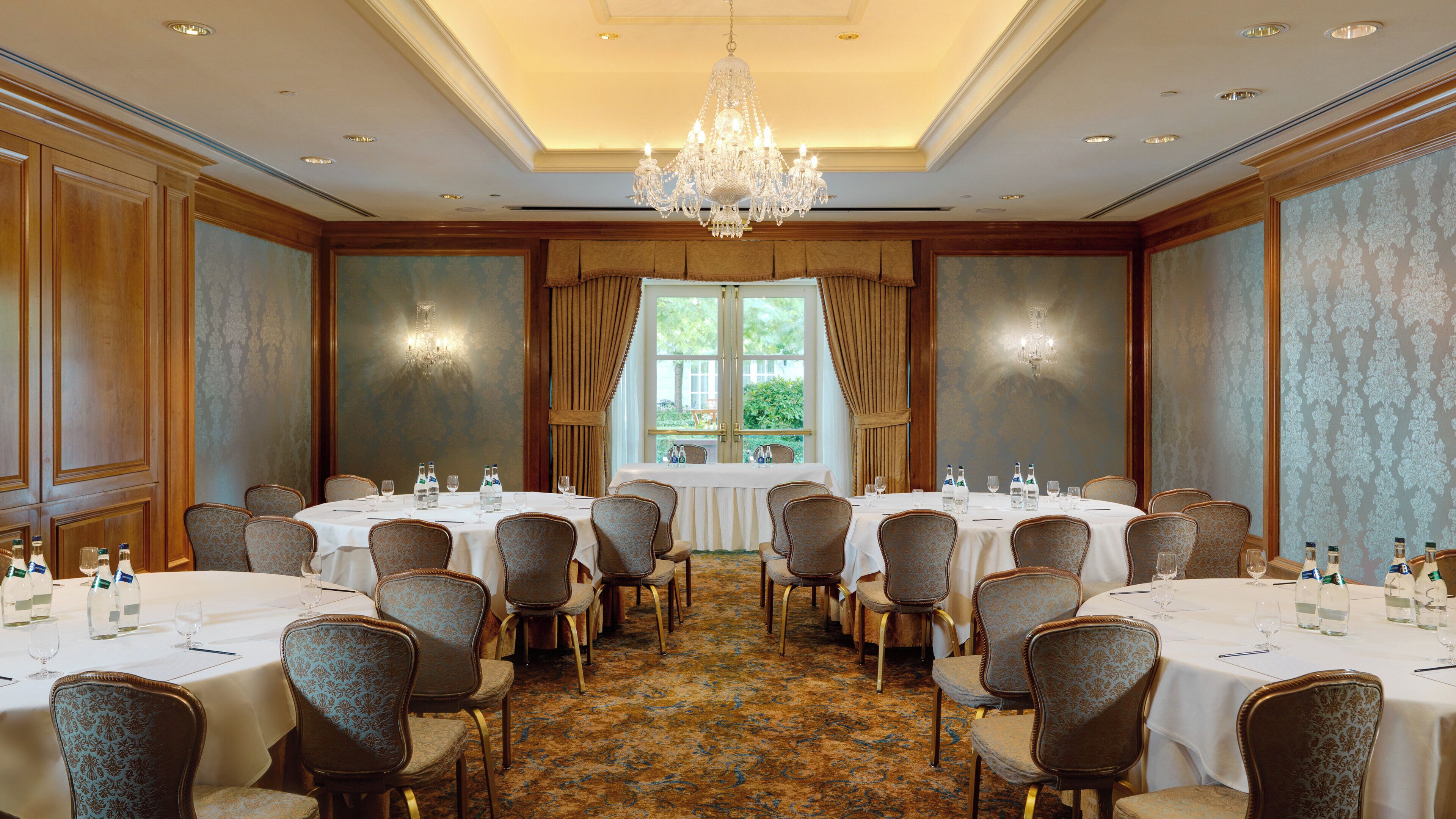 A conference room with round tables, chairs, and a chandelier.