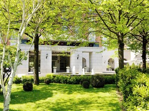 A building with a stone facade, arched entrance, and a well-maintained garden with a fountain. - InterContinental Dublin by IHG (Dublin)