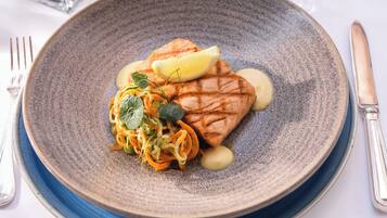 Ein Teller mit gegrilltem Lachs, Zitronenscheiben und einer Portion gebratenem Gemüse.