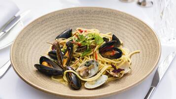 A plate of pasta with mussels and greens.