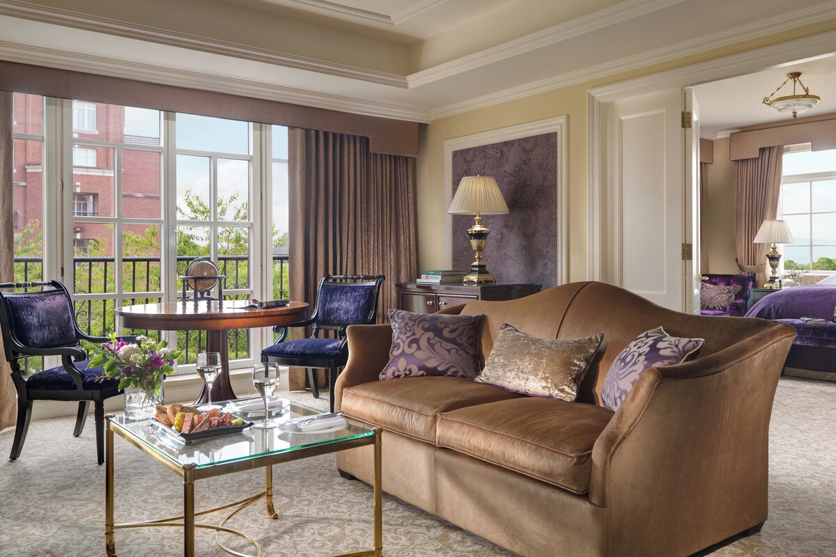 A well-appointed living room with a leather sofa, a glass coffee table, and a view of a balcony.