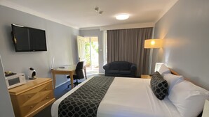 Una camera d'albergo con un letto, una scrivania, una sedia, una televisione e una finestra con tende.